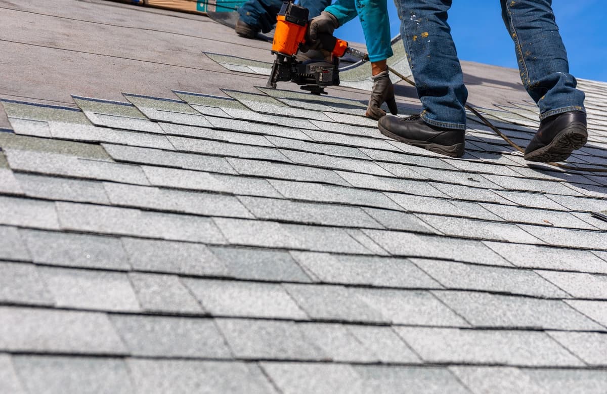 Professional roofer installing asphalt shingles